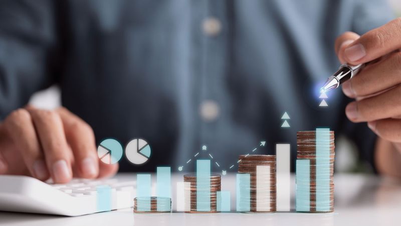 Person analyzing financial growth with calculator, money stacks, and charts, highlighting business investment insights.