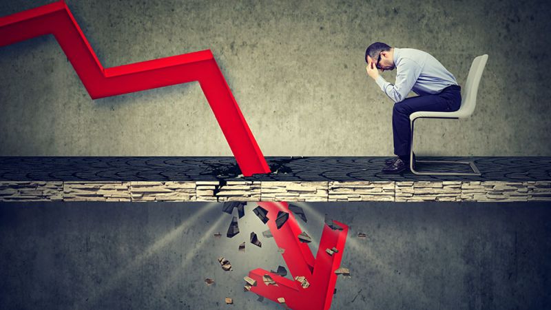 Businessman stressed by declining financial graph breaking the surface.